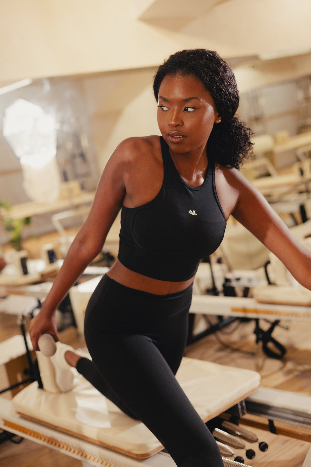 The Reformer Set in Black: Pulse Bra in a lunge on the reformer
