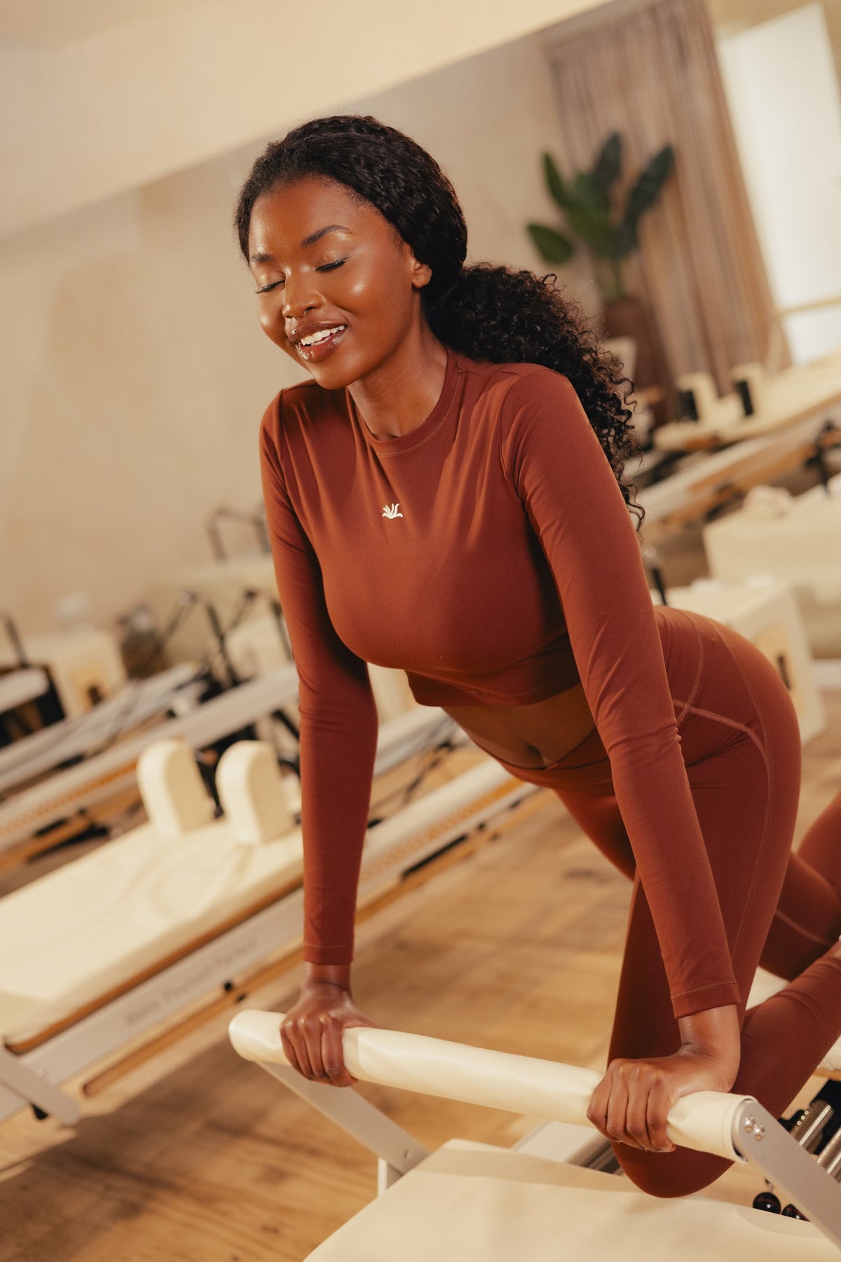 VYVRA Athletic Long Sleeve Top in Chocolate Brown on the reformer
